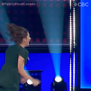 a woman in a green dress is dancing on a stage in front of a blue wall .