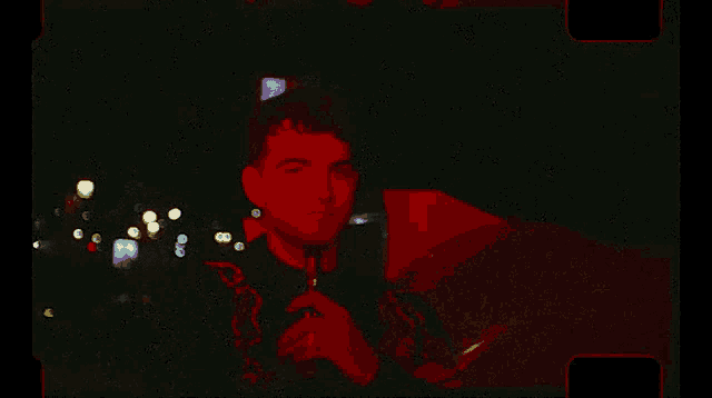 a man is holding a camera in a dark room with red lights behind him