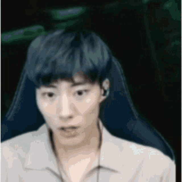 a man with blue hair is sitting in a chair with headphones on .