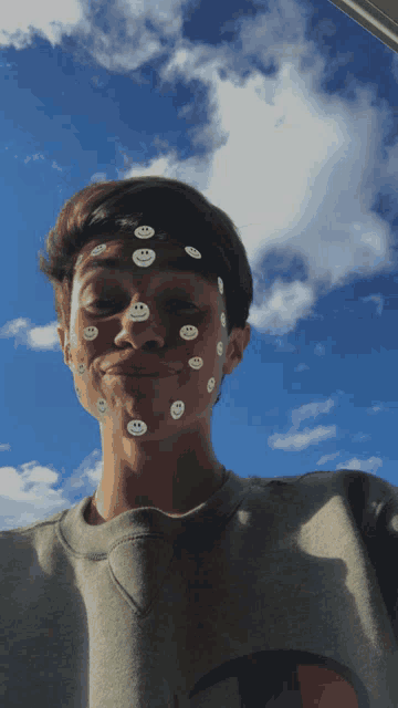 a boy with smiley faces on his face and a champion shirt