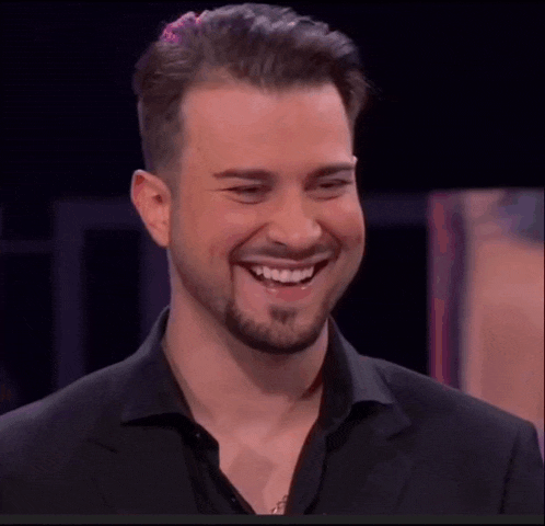 a man with a beard is smiling in a black shirt