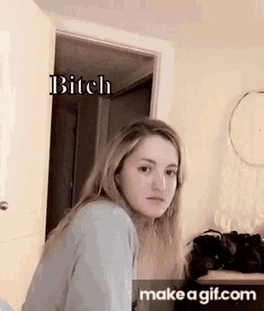 a woman is standing in front of a door with the words `` bitch '' on it .