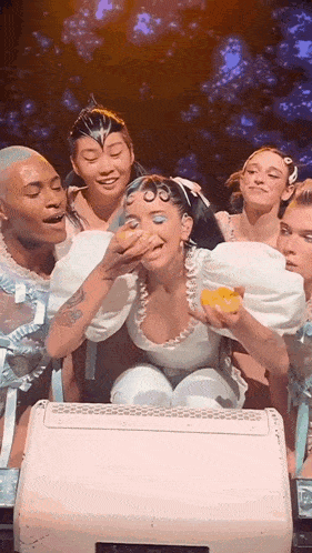 a group of people are standing around a woman holding a donut in her hand .