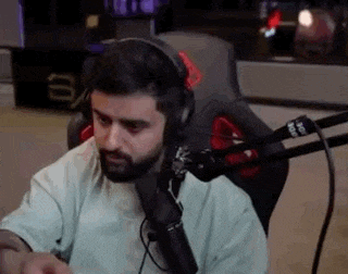 a man with a beard is sitting in front of a microphone .