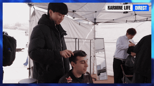 a man getting his hair cut under a tent with karmine life direct written on the bottom
