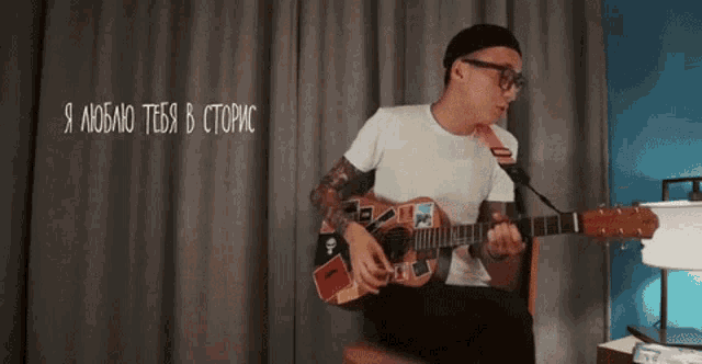 a man is playing a guitar in front of a microphone .