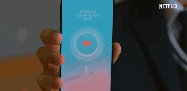 a person is holding a smart phone with a heart on the screen and a netflix logo in the background