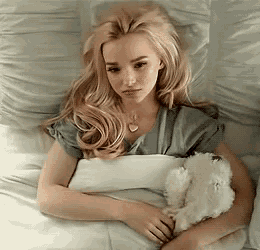 a woman is laying in bed with a teddy bear in her lap .