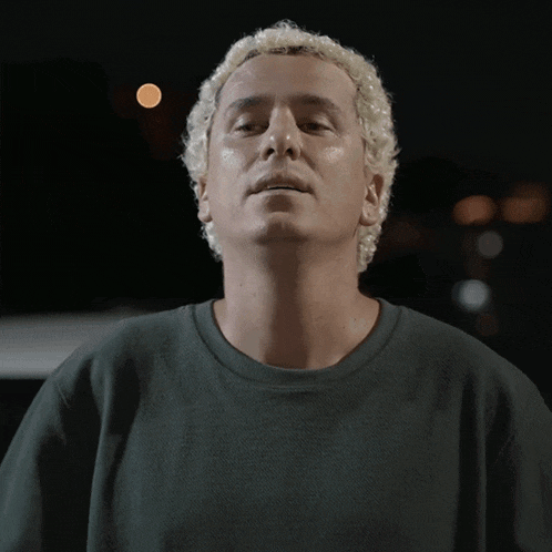 a man with blonde hair is wearing a black shirt and says que e que aconteceu