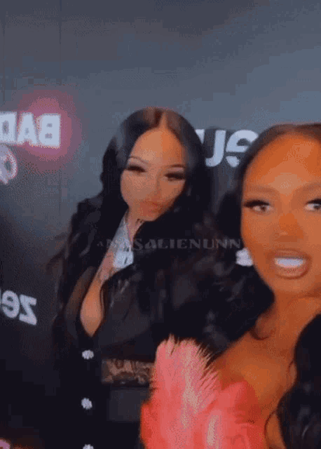 two women are posing for a picture and one of them is wearing a pink feathered top
