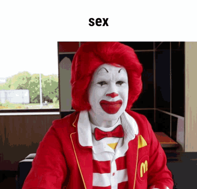 a clown with red hair and white face is wearing a red mcdonald 's uniform