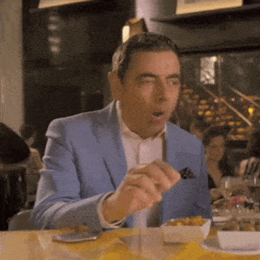 a man in a blue suit is sitting at a table eating