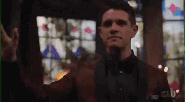 a man in a suit is standing in front of a stained glass window in a church .