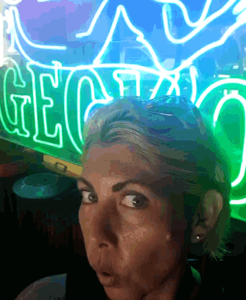 a woman is standing in front of a neon sign that says geico