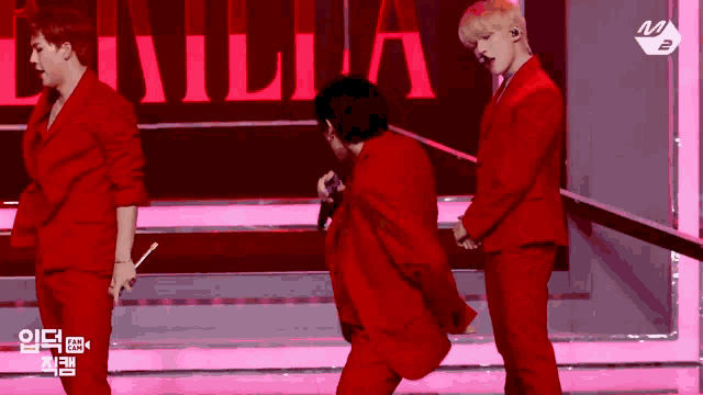 a man in a red suit is holding a microphone while standing next to two other men .