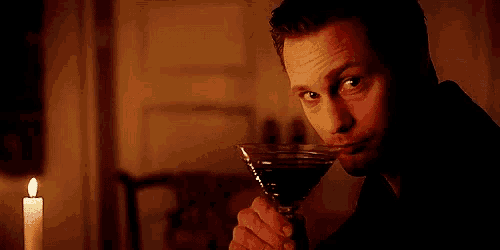 a man is drinking a martini in a dark room .