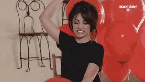 a woman is surrounded by red balloons with marie claire written on the balloons