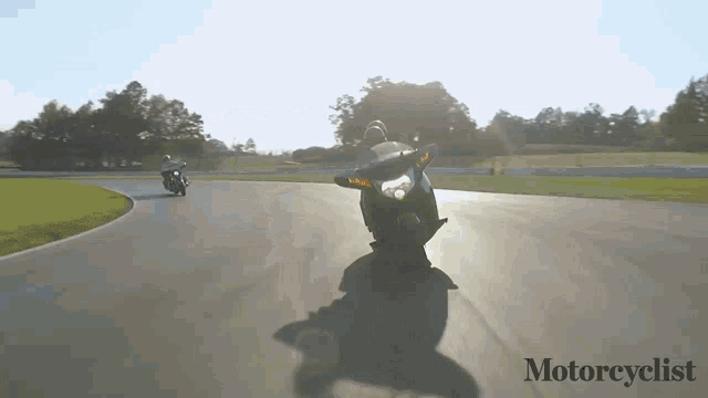 two motorcycles are on a track with the words motorcyclist on the bottom right