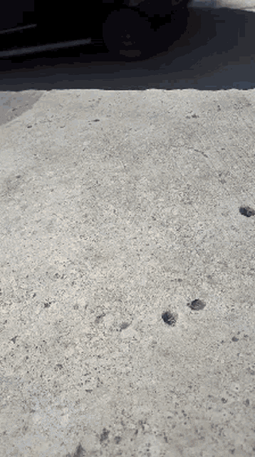 a black car is parked on the side of a road next to a concrete surface .