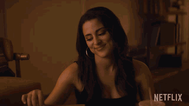 a woman is sitting at a table with a netflix logo on the bottom