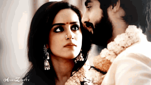 a woman with a nose ring is looking at a man with a flower garland around his neck