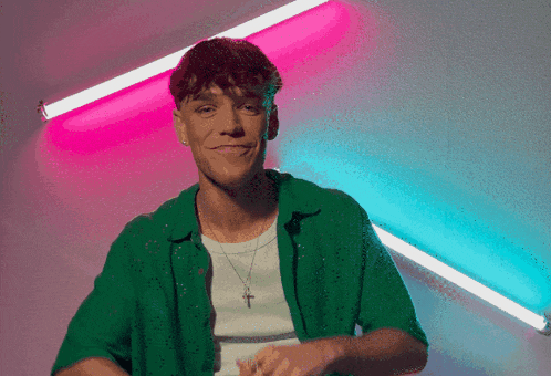 a man wearing a green shirt and a cross necklace smiles