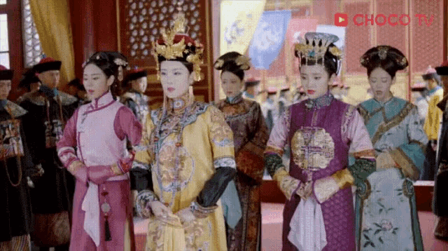a group of women are standing in a room wearing traditional chinese clothing .