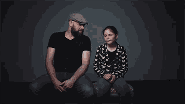 a man and a girl are sitting next to each other looking at each other