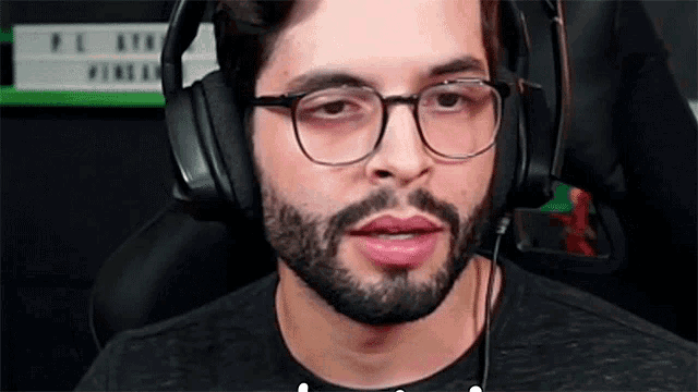 a man with a beard and glasses is wearing headphones and a microphone .