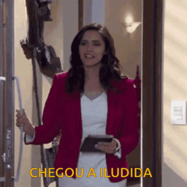 a woman in a red jacket is standing in front of a door holding a tablet and a cell phone ..