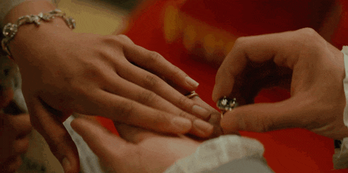 a close up of a person putting a ring on another person 's finger