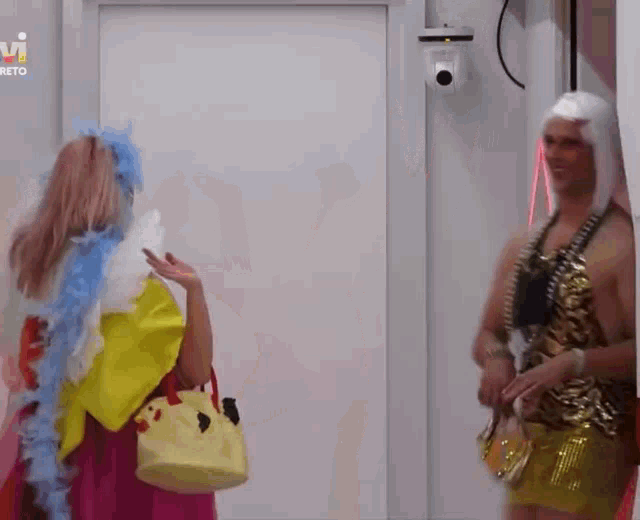 a woman in a pink dress is standing next to a man in a gold outfit .