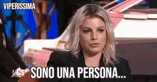 a woman with blonde hair is sitting in front of a piano and says sono una persona .