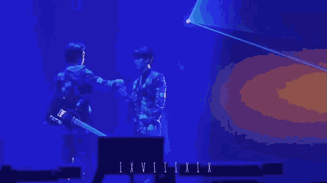 two men shaking hands on a stage with the letters ixvi ii ix on the bottom