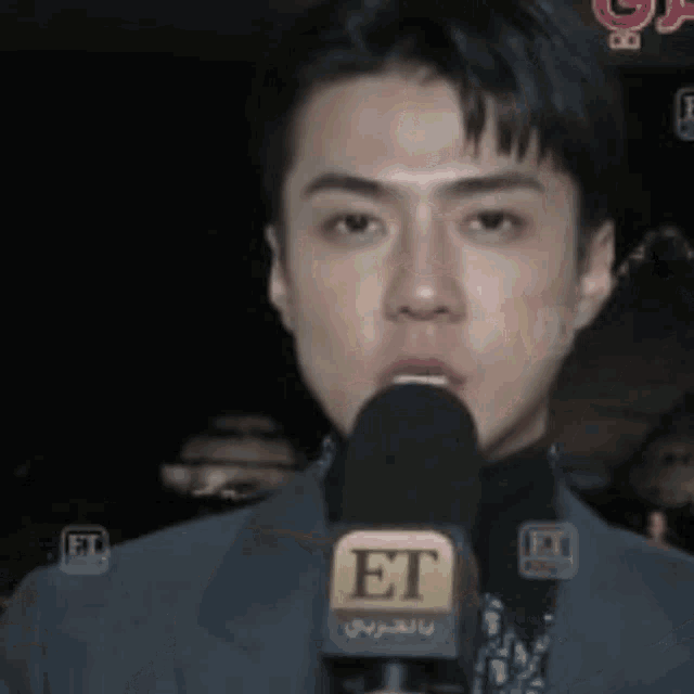 a man in a suit is speaking into a microphone with the word et on it .