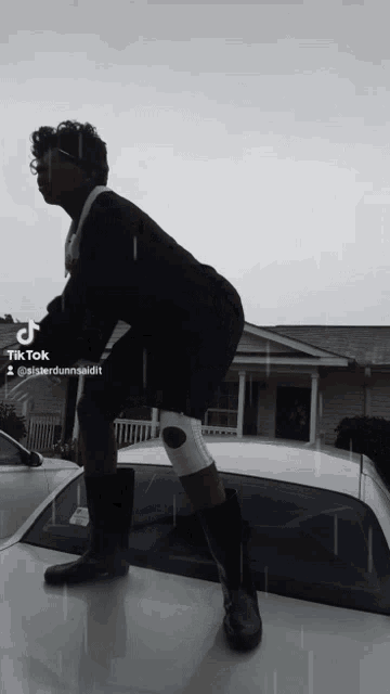 a man with a knee brace standing on top of a car