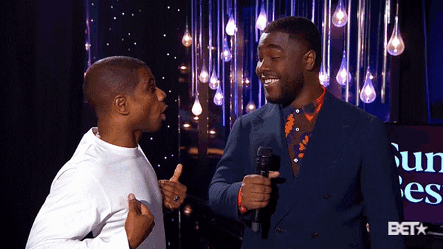 two men standing next to each other with a bet logo in the background