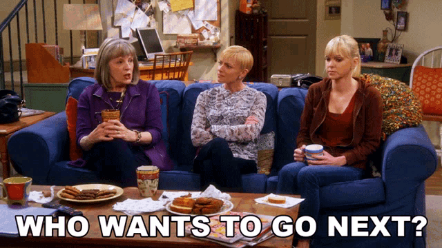 three women are sitting on a couch with the words who wants to go next
