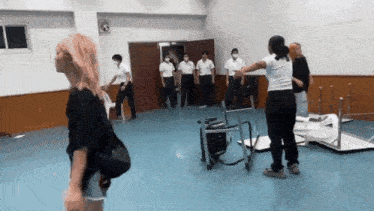 a group of people are standing in a room with tables and chairs .