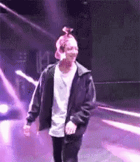 a man wearing a black jacket and a white shirt is walking on a stage .