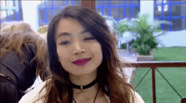 a woman wearing a choker and a necklace is smiling .