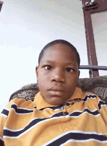 a young boy wearing a yellow and black striped shirt with the letter p on the collar