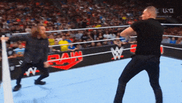 two men are wrestling in a wrestling ring with a raw banner in the background