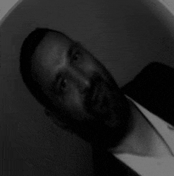 a black and white photo of a man with a beard wearing a suit .