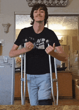a man with crutches is wearing a black shirt with a picture of a motorcycle on it