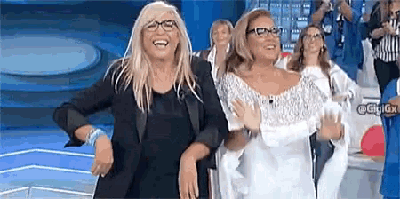 two women are dancing on a stage and one has glasses on