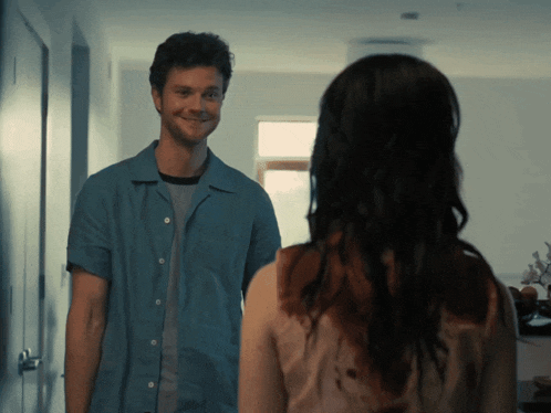 a man in a blue shirt is smiling at a woman