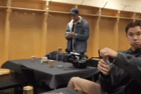 a man in a blue jacket stands in a locker room