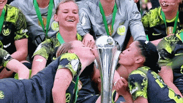 a group of female soccer players are kissing a trophy and one has the number 1 on her jersey