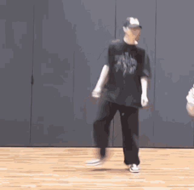 a man is dancing on a wooden floor in a room while another man watches .